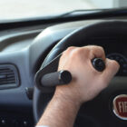 Mano usando empuñadora con dos pomos para volante